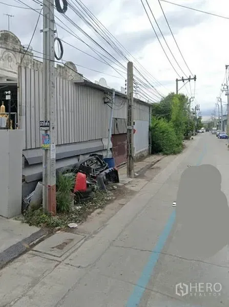 货栈 出售在Phra Samut Chedi, Samut Prakan - 仓库侧立面与安静街道相邻，电线杆与绿化带在旁。