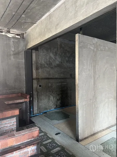 零售空间 出租在Watthana, Bangkok - 雨棚下的侧向视图，展示砖吧台、混凝土墙与水磨石地面