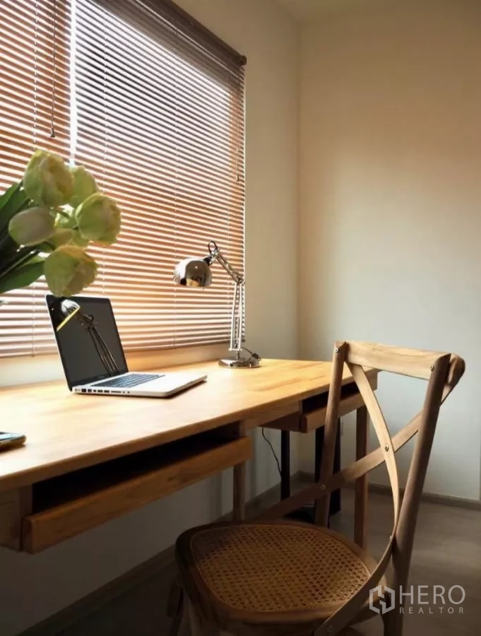 Townhouse for rent in Bang Phli, Samut Prakan - Compact home office corner with wooden desk, laptop, task lamp and window blinds.