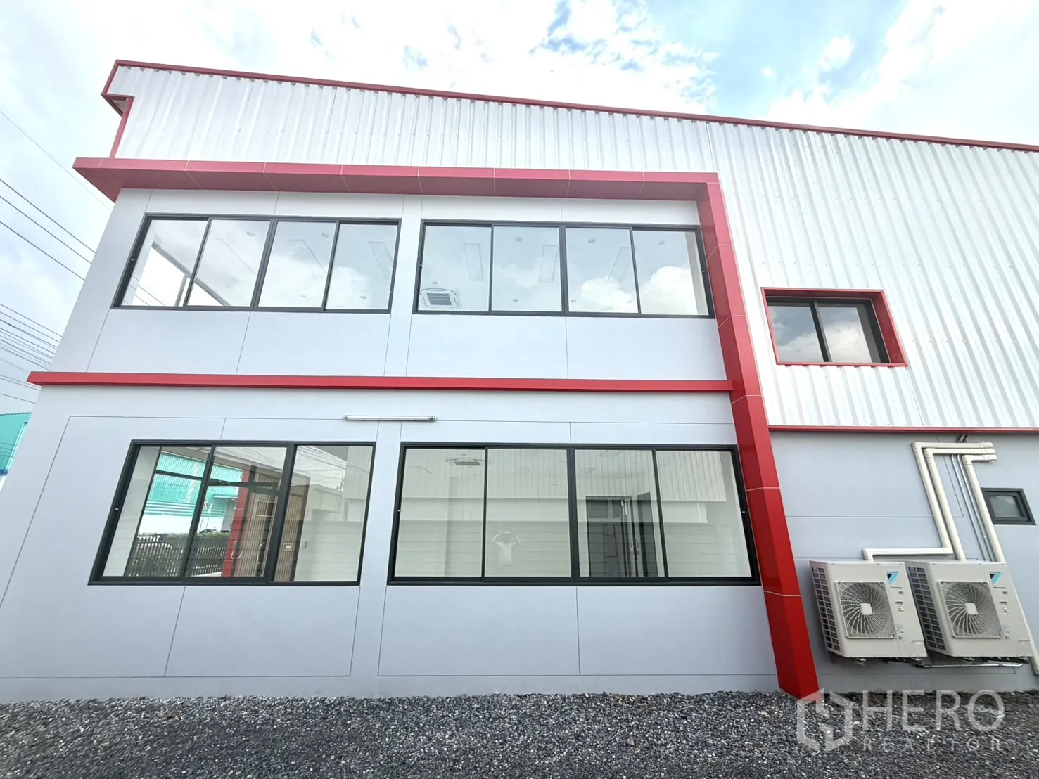 Factory for rent or sale in Lam Luk Ka, Pathum Thani - Side elevation showing office windows and outdoor air-conditioning units.