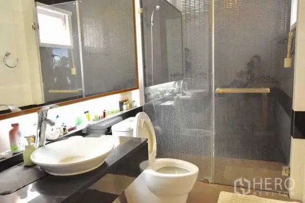 Detached House for sale in Bueng Kum, Bangkok - Modern bathroom with vessel sink, backlit mirror and glass-enclosed shower with dark mosaic tiles.