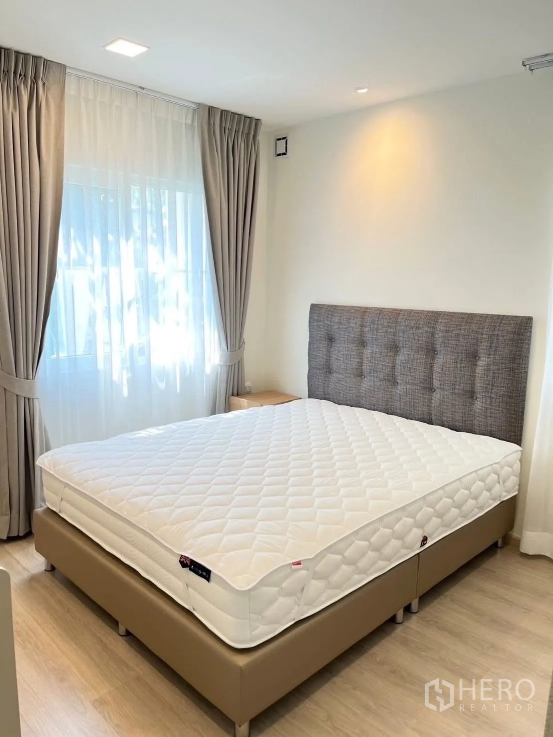 Detached House for rent in Bang Phli, Samut Prakan - Sunlit bedroom with upholstered headboard bed and double windows with curtains.