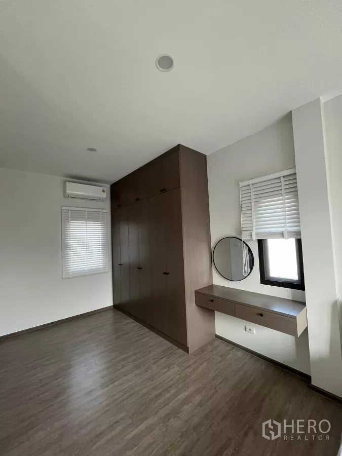 Detached House for rent or sale in Bang Phli, Samut Prakan - Master dressing area with wall-length wardrobe and floating vanity with round mirror.