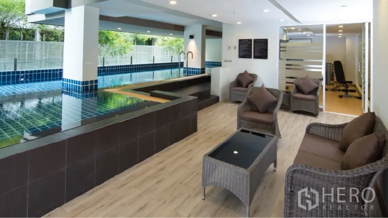 Condominium for rent or sale in Watthana, Bangkok - Indoor swimming pool with lounge seating and large windows.