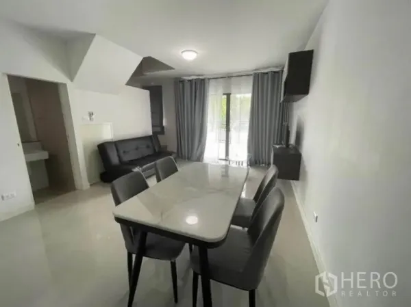 Townhouse for rent in Phasi Charoen, Bangkok - Bright open-plan living and dining area with marble-top table, sofa and sliding glass doors.