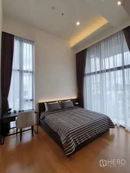 Condominium for rent in Watthana, Bangkok - Primary bedroom with floor-to-ceiling windows, desk, and city views in a high-ceiling condo.