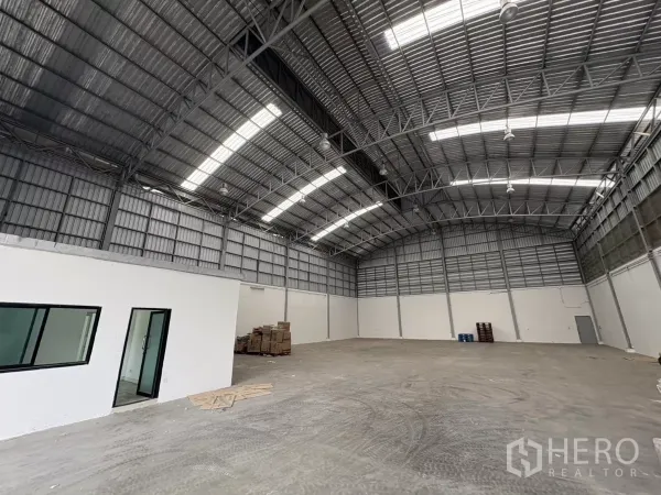 Warehouse for rent in Bang Phli, Samut Prakan - Warehouse interior with a white office room and windows beneath the high roof.