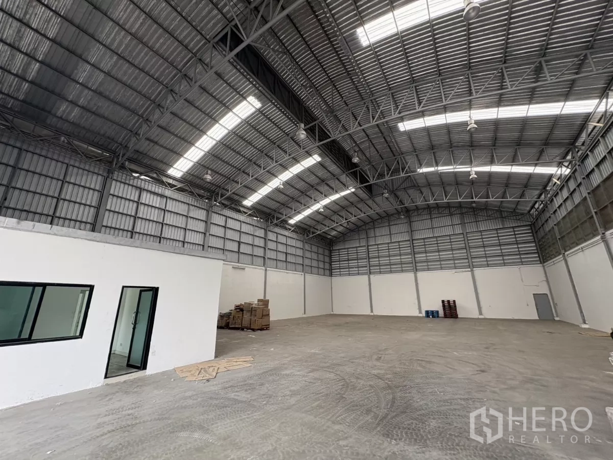 Warehouse for rent in Bang Phli, Samut Prakan - Warehouse interior with a white office room and windows beneath the high roof.