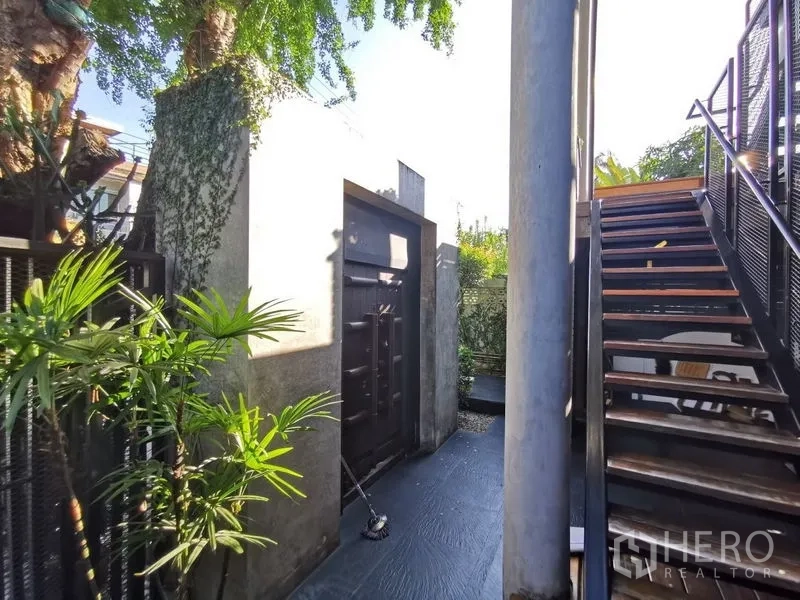 Home Office for sale in Wang Thonglang, Bangkok - Side entrance with concrete gate, outdoor staircase and tropical planting.