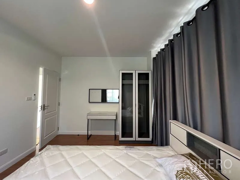 บ้าน ให้เช่าในBang Kapi, Bangkok - มุมห้องนอนพร้อมโต๊ะเครื่องแป้งและตู้เสื้อผ้าสูงข้างผ้าม่านสีเทา