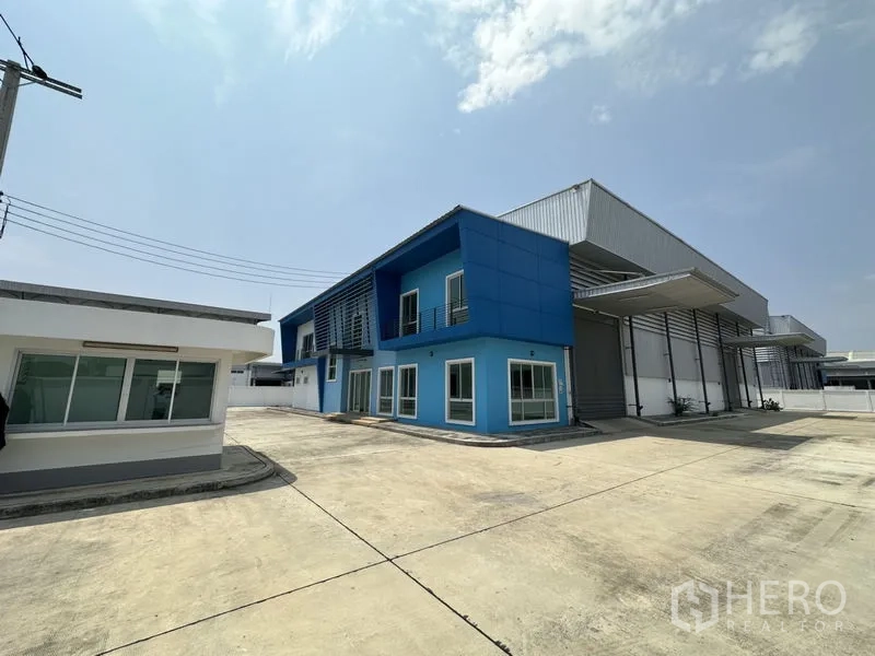 工厂 出租在Bang Sao Thong, Samut Prakan - 工厂外观侧拍，可见门卫室、遮雨装卸雨棚和宽敞的货车回转场地。