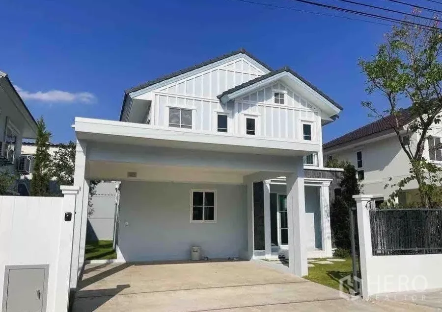 Detached House for rent or sale in Bang Phli, Samut Prakan - Modern white detached house with covered carport in a Srinakarin–Bangna estate under a clear blue sky.