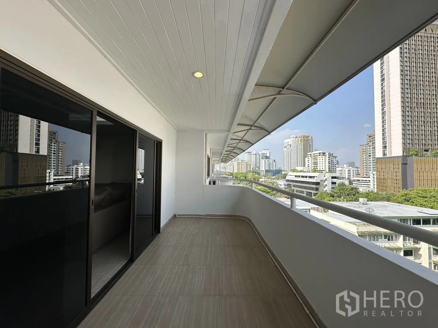 Condominium for rent in Watthana, Bangkok - Long covered balcony accessed by sliding doors, overlooking the city.