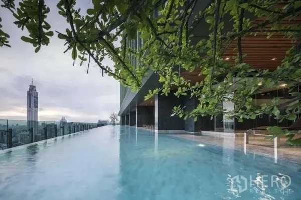 Condominium for sale in Ratchathewi, Bangkok - Rooftop infinity-edge swimming pool with skyline views framed by leafy branches.