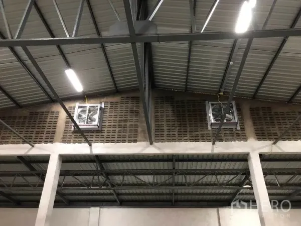 Warehouse for rent in Pak Kret, Nonthaburi - Close-up of industrial roof structure with ventilation fans, steel beams and energy-efficient lights.