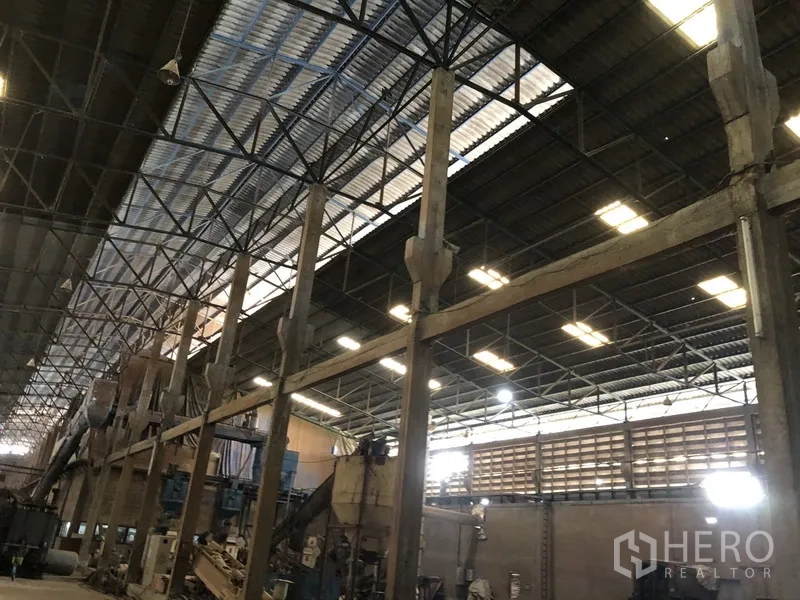 工厂 出租在Bang Bua Thong, Nonthaburi - 近景展示钢桁架屋顶与立柱，屋面设采光天窗