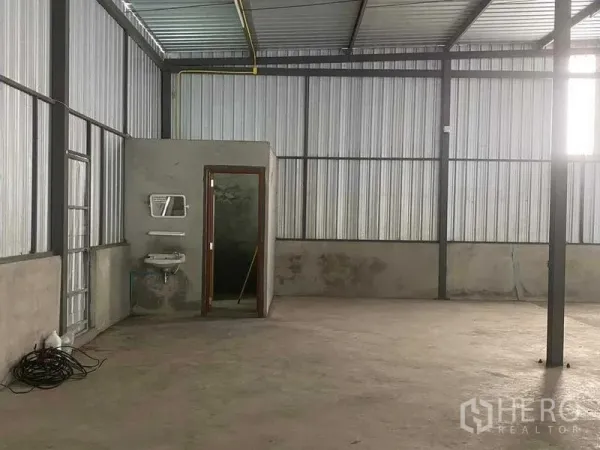 Warehouse for rent in Nong Khaem, Bangkok - Warehouse corner showing built-in restroom with sink and concrete walls.