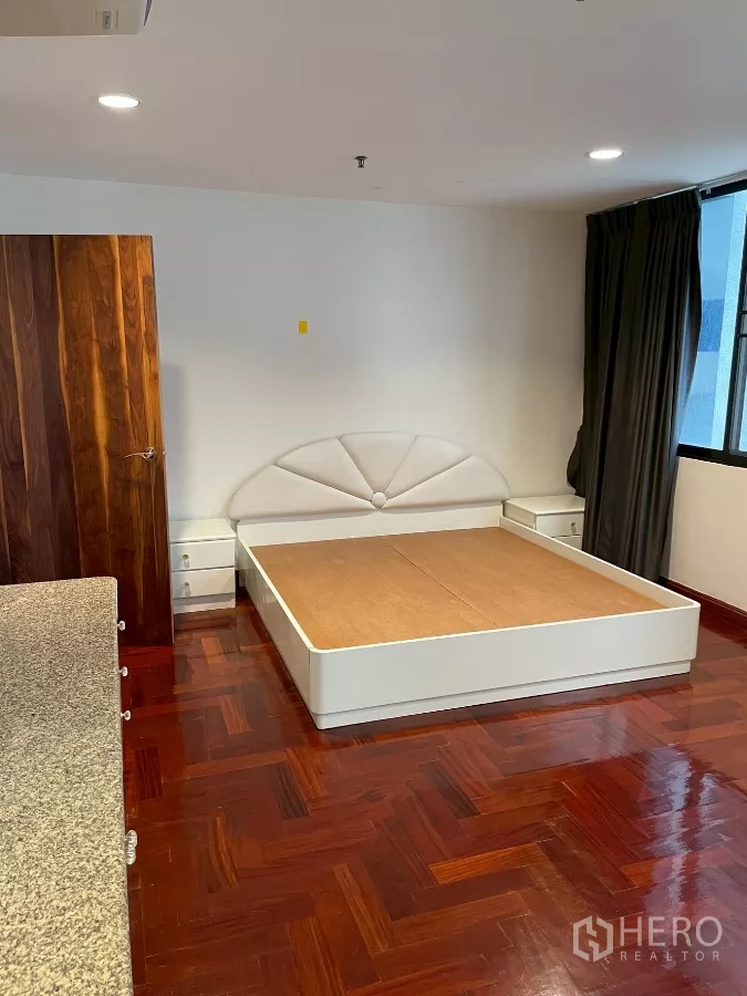 คอนโด ขายในWatthana, Bangkok - ห้องนอนพร้อมเตียงแพลตฟอร์มสีขาว โต๊ะข้างเตียง และไฟดาวน์ไลท์