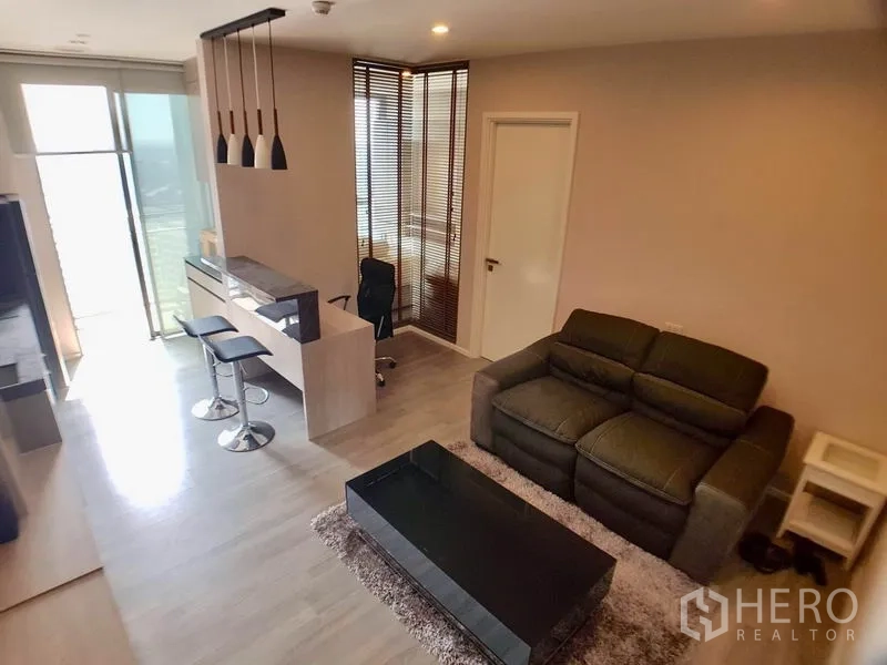 คอนโด ขายในWatthana, Bangkok - พื้นที่นั่งเล่นสว่างเชื่อมระเบียง มีโต๊ะทำงานและเคาน์เตอร์บาร์ไฟห้อย ในคอนโด 1 ห้องนอนใกล้บีทีเอสพระโขนง