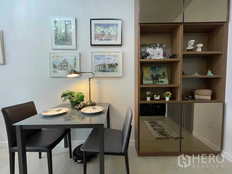 Condominium for sale in Huai Khwang, Bangkok - Two-seat dining set beside built-in shelving and framed artwork on the wall.