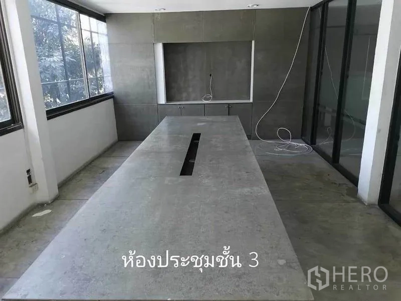 Home Office for rent in Khlong Toei, Bangkok - Bright meeting room with a long table, large windows, and built-in cabinets.