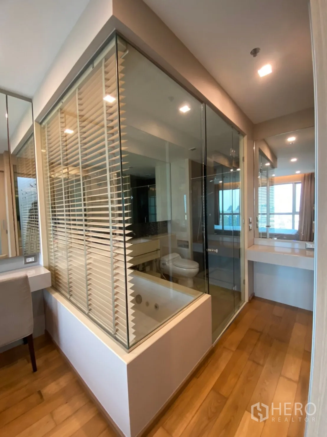 Condominium for rent in Ratchathewi, Bangkok - Glass-walled bathroom featuring a soaking tub, separate shower, vanity and warm wood flooring.