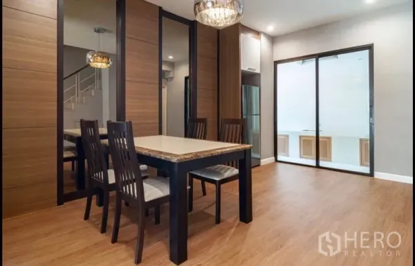 ทาวน์เฮาส์ ขายในKhlong Toei, Bangkok - พื้นที่รับประทานอาหารพร้อมโคมระย้า โต๊ะท็อปหิน ผนังลายไม้ กระจกเงา และประตูกระจกสไลด์