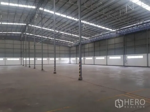 Warehouse for rent in Si Racha, Chon Buri - Spacious warehouse interior showing steel columns, clear-span roof trusses, and skylight strips.