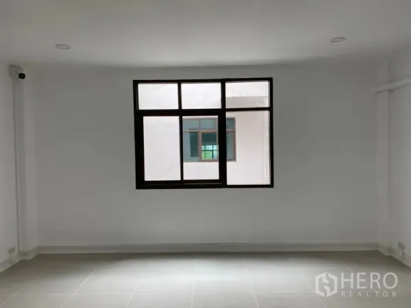 Home Office for rent in Wang Thonglang, Bangkok - Empty white room with large window and grey tiled floor.