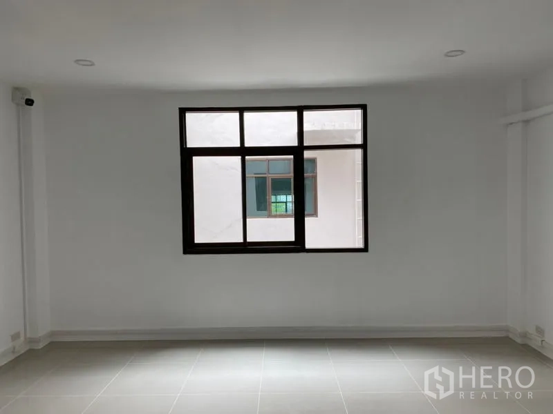 Home Office for rent in Wang Thonglang, Bangkok - Empty white room with large window and grey tiled floor.