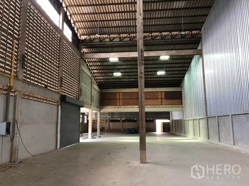 货栈 出租在Pathum Thani - 开阔储存大厅，中心立柱与金属板墙面。