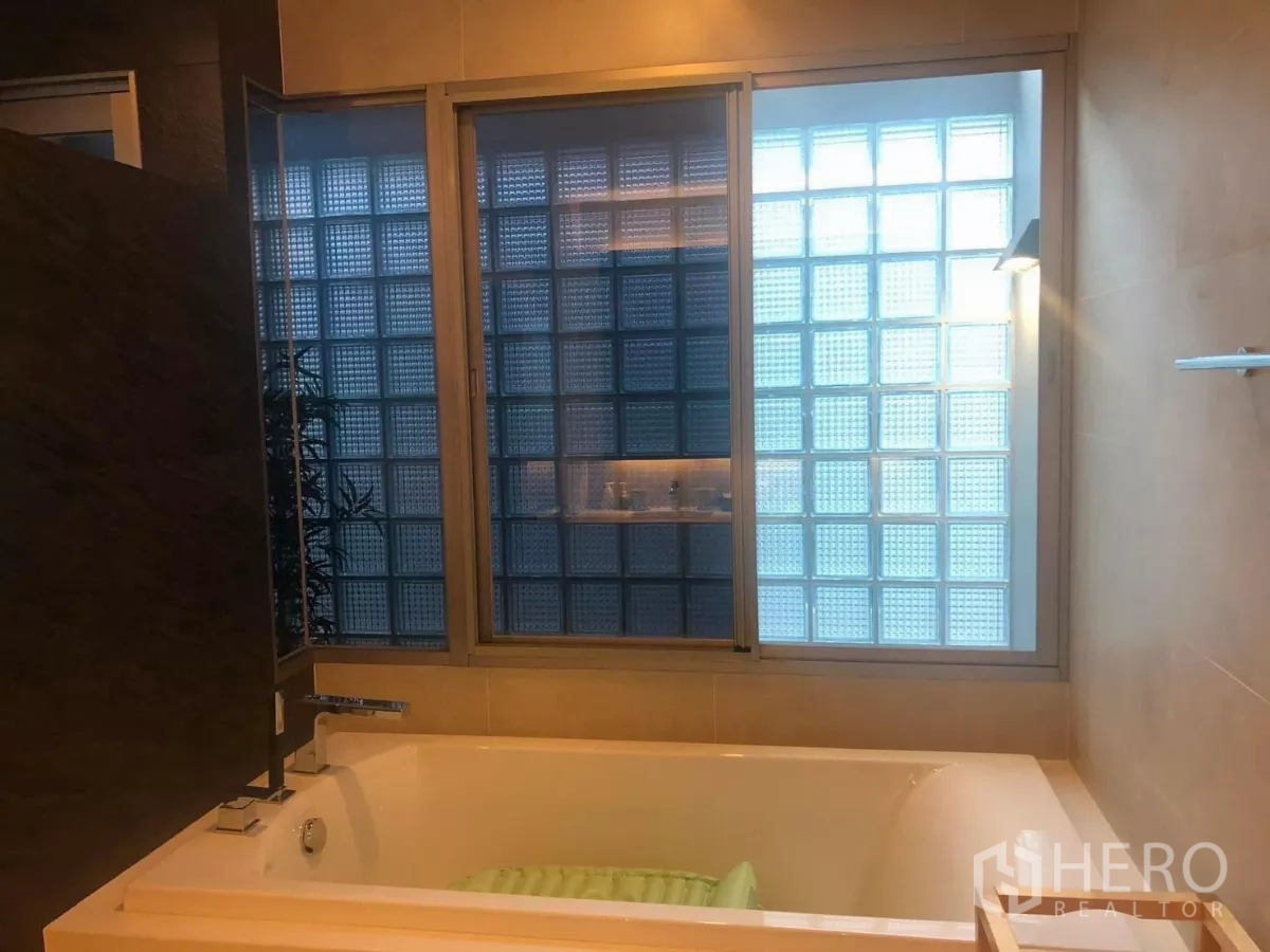Detached House for rent in Bang Kapi, Bangkok - Bathroom featuring soaking bathtub next to frosted glass-block windows.