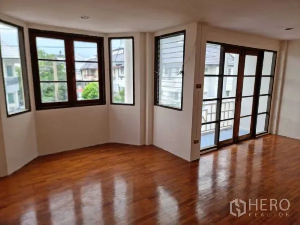 ทาวน์เฮาส์ ให้เช่าในWang Thonglang, Bangkok - ห้องมุมสว่างพื้นไม้ มีหน้าต่างบานกระทุ้งและประตูกระจกออกสู่ระเบียง มองเห็นบ้านในละแวก