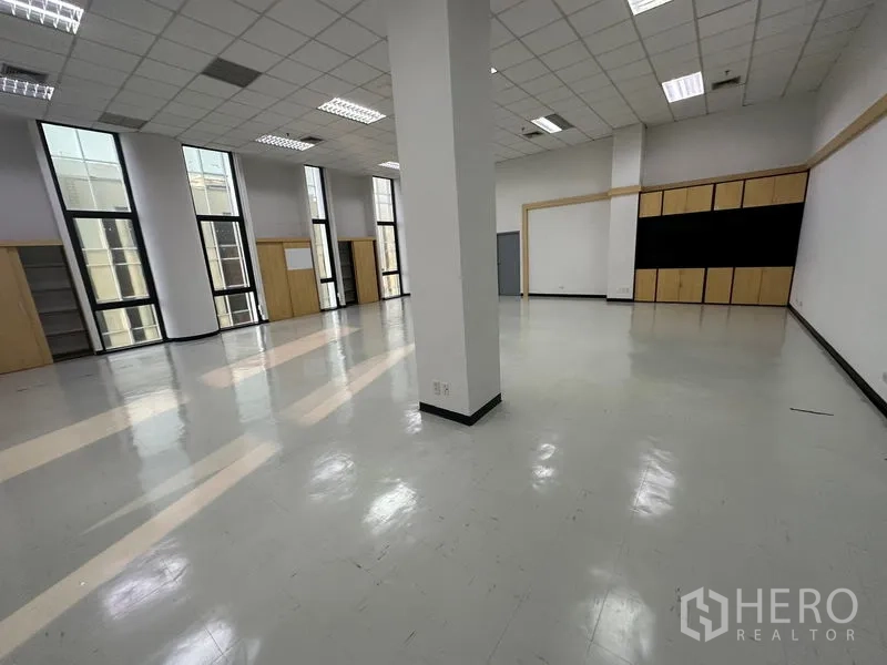 สำนักงาน ให้เช่า - พื้นที่ทำงานโอเพ่นสเปซกว้าง พื้นเงา ฝ้าทีบาร์ เสากลาง และหน้าต่างแนวตั้งให้แสงสว่างทั่วถึง