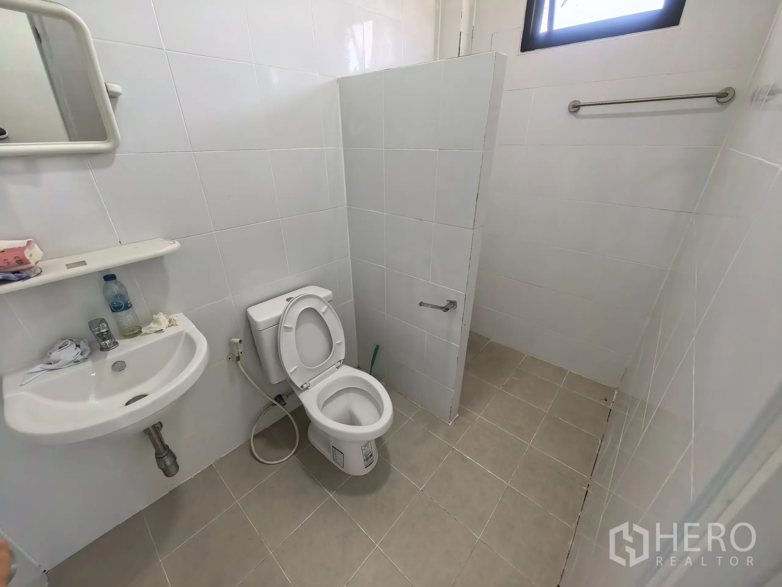 Factory for rent or sale in Khlong Toei, Bangkok - Clean staff restroom with toilet, sink, tiled walls, and a small window for ventilation.