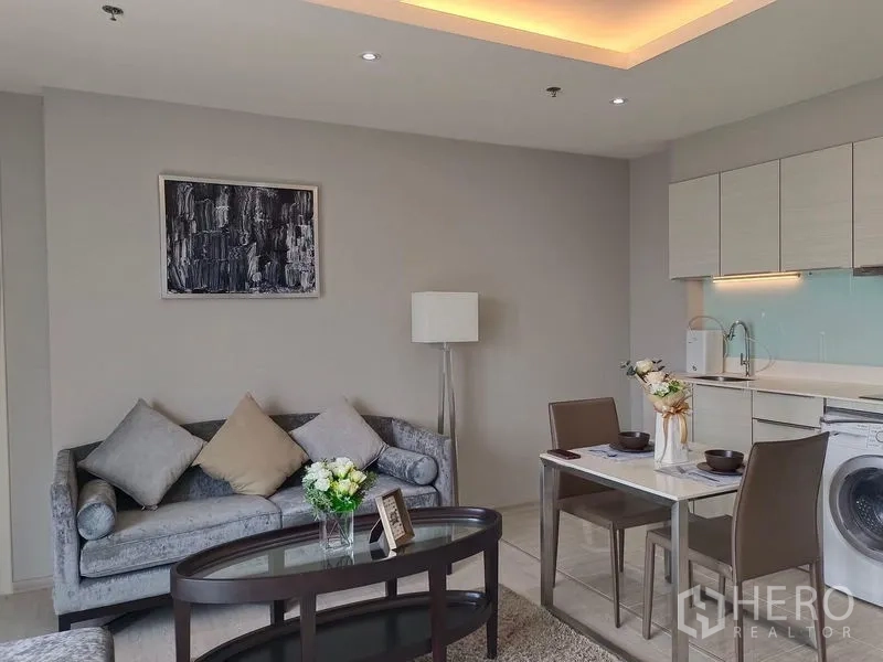 คอนโด ให้เช่าในWatthana, Bangkok - มุมมองโซฟาพร้อมครัวขนาดกะทัดรัด ไฟใต้ตู้ และเครื่องซักผ้าในห้อง