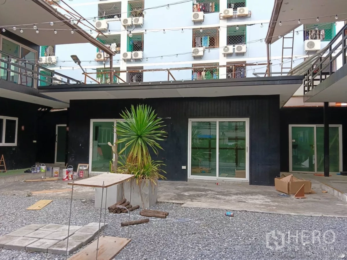 零售空间 出租在Huai Khwang, Bangkok - 庭院视角，黑色立面建筑、推拉门与花盆。