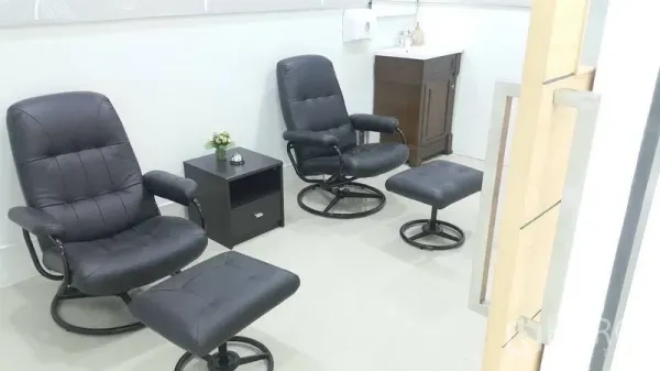 Shophouse for rent in Khan Na Yao, Bangkok - Small lounge or treatment area with two black recliners, matching footstools, side cabinet and a compact sink.