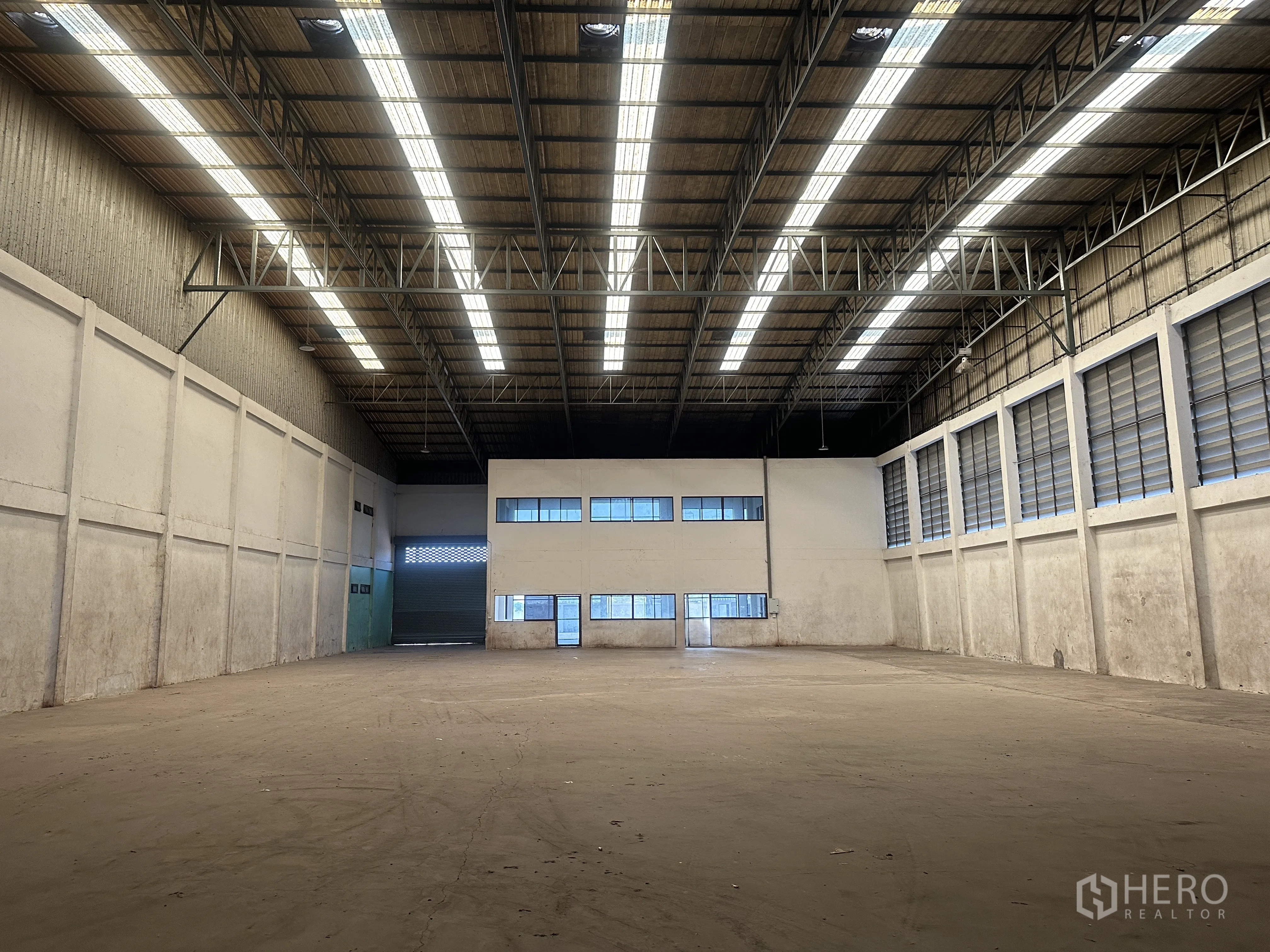 Factory for rent in Wang Noi, Phra Nakhon Si Ayutthaya - Large warehouse interior with a high steel-truss roof, skylight strips, and an internal office block.