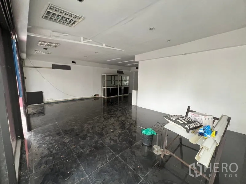 零售空间 出租在Watthana, Bangkok - 宽阔店铺空间，黑色地砖与储物架，待装修。