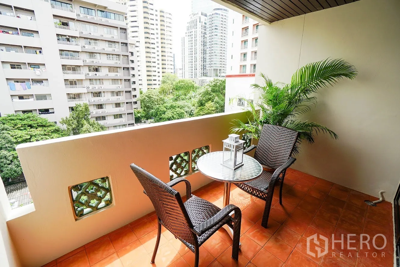 房间 出租在Watthana, Bangkok - 私享阳台，藤椅茶几与城市景观。