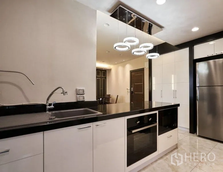 Condominium for sale in Ratchathewi, Bangkok - Sleek kitchen with sink, cooktop, built-in appliances and circular pendant lighting.
