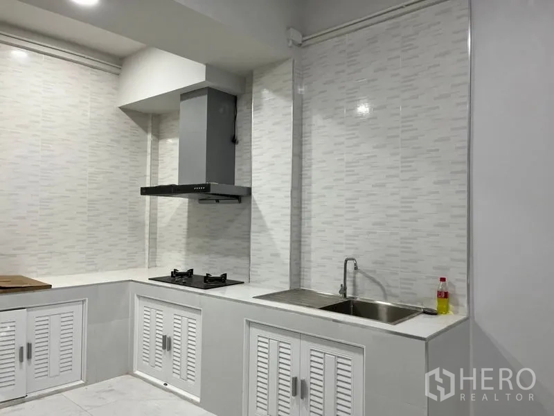 ทาวน์เฮาส์ ให้เช่าในDin Daeng, Bangkok - ครัวบิลต์อินโทนขาว เคาน์เตอร์รูปตัวแอล เตาแก๊ส เครื่องดูดควัน และอ่างล้างจาน.