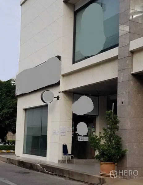 零售空间 出租在Khlong Toei, Bangkok - 一层店铺门面，通高落地玻璃与入口雨棚，门前摆放绿植。