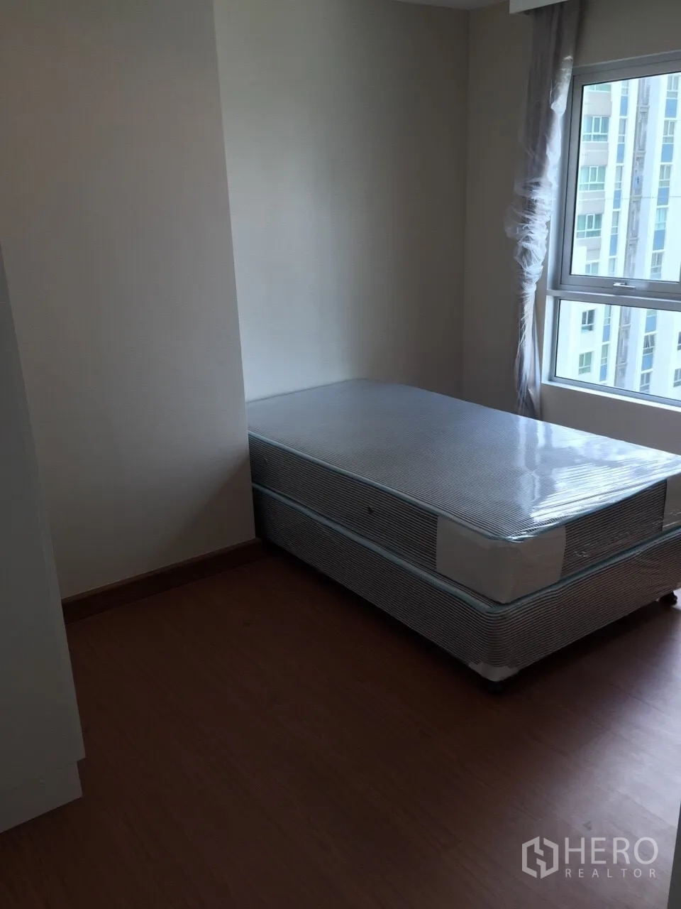 Condominium for rent in Huai Khwang, Bangkok - Bright bedroom with single bed base, large window and city view in the Rama 9 area.