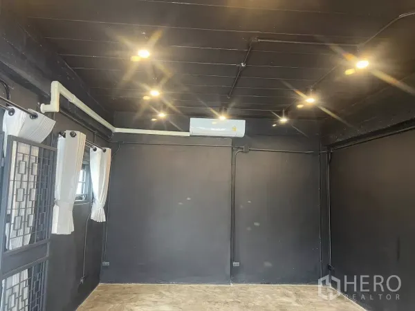 带办公室的家 出租在Wang Thonglang, Bangkok - 黑色墙面与射灯的工作室房间，带空调和带窗帘的窗户。