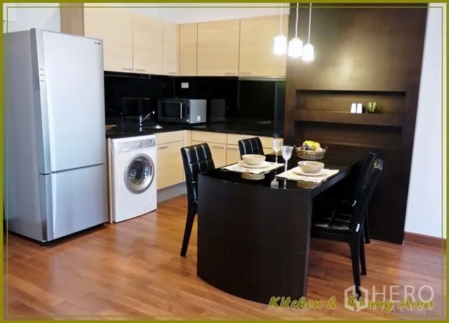 คอนโด ให้เช่าในPathum Wan, Bangkok - ครัวสมัยใหม่ตู้ไม้สีอ่อน เคาน์เตอร์สีดำ ตู้เย็น เครื่องซักผ้า ไมโครเวฟ และโต๊ะรับประทานอาหารสีเข้มสำหรับสี่ที่นั่งใต้โคมไฟแขวน