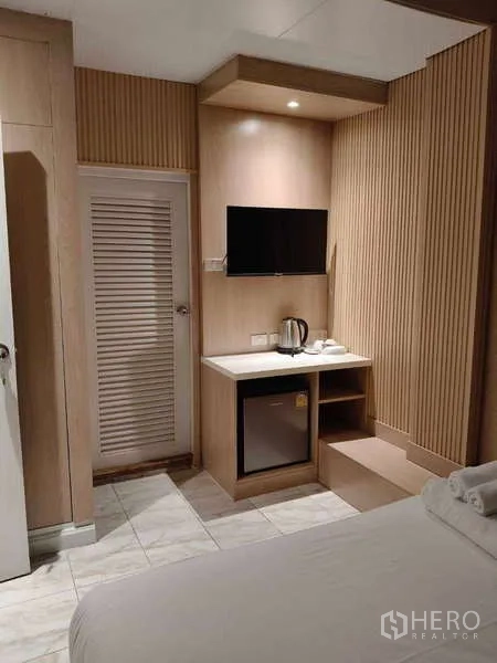 零售空间 出租在Khlong Toei, Bangkok - 内置台面配电视、小冰箱与热水壶，旁有百叶门。