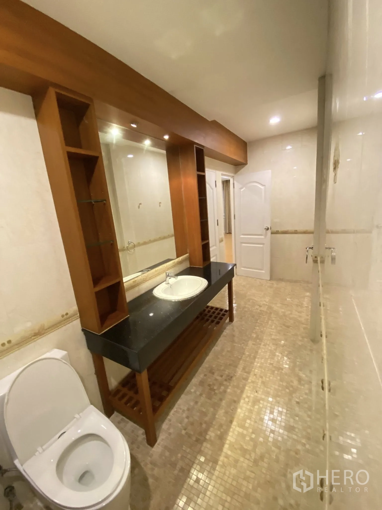 Home Office for rent in Pathum Wan, Bangkok - Bathroom featuring a long granite countertop vanity with mirror, wood shelving, and toilet.