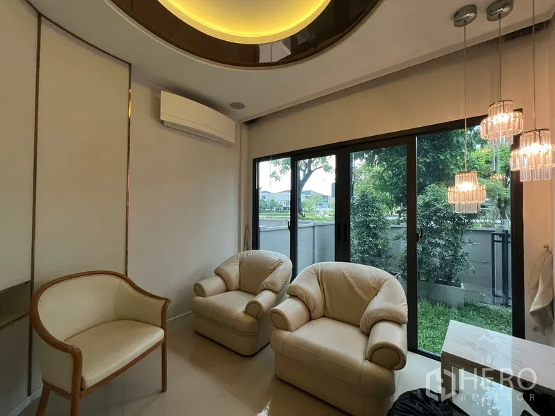 บ้าน ให้เช่าในSaphan Sung, Bangkok - มุมนั่งเล่นอบอุ่น เก้าอี้นวม โคมแขวน และประตูกระจกสไลด์ออกสู่สวน